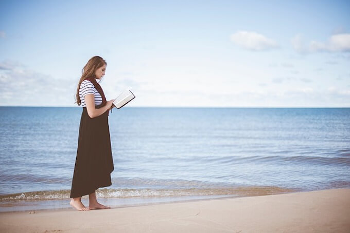 海辺で読書をしている女性